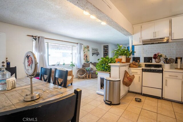 kitchen with white cabinetry, a textured ceiling, kitchen peninsula, white range oven, and backsplash