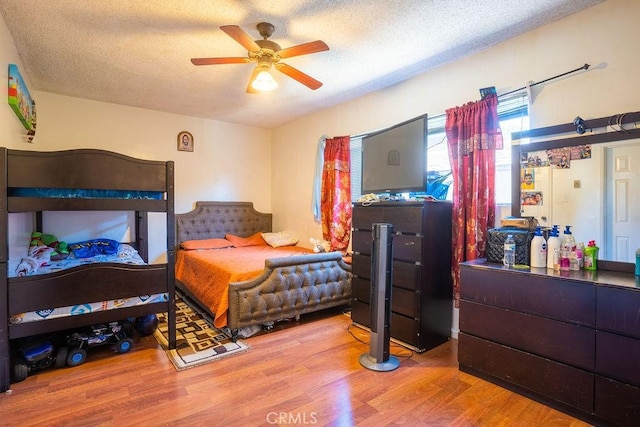 bedroom with hardwood / wood-style flooring, ceiling fan, and a textured ceiling