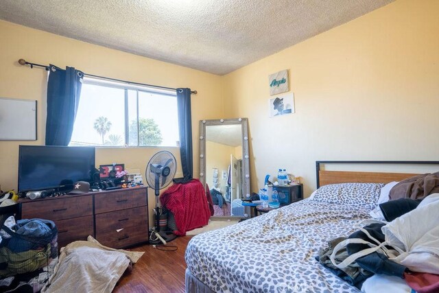 bedroom with dark hardwood / wood-style floors and a textured ceiling