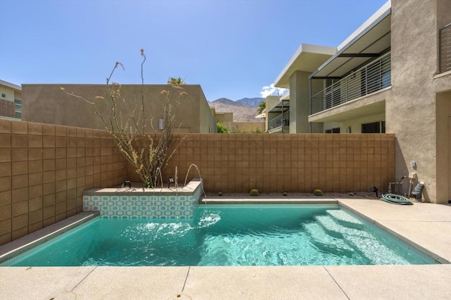 view of swimming pool with pool water feature and a mountain view