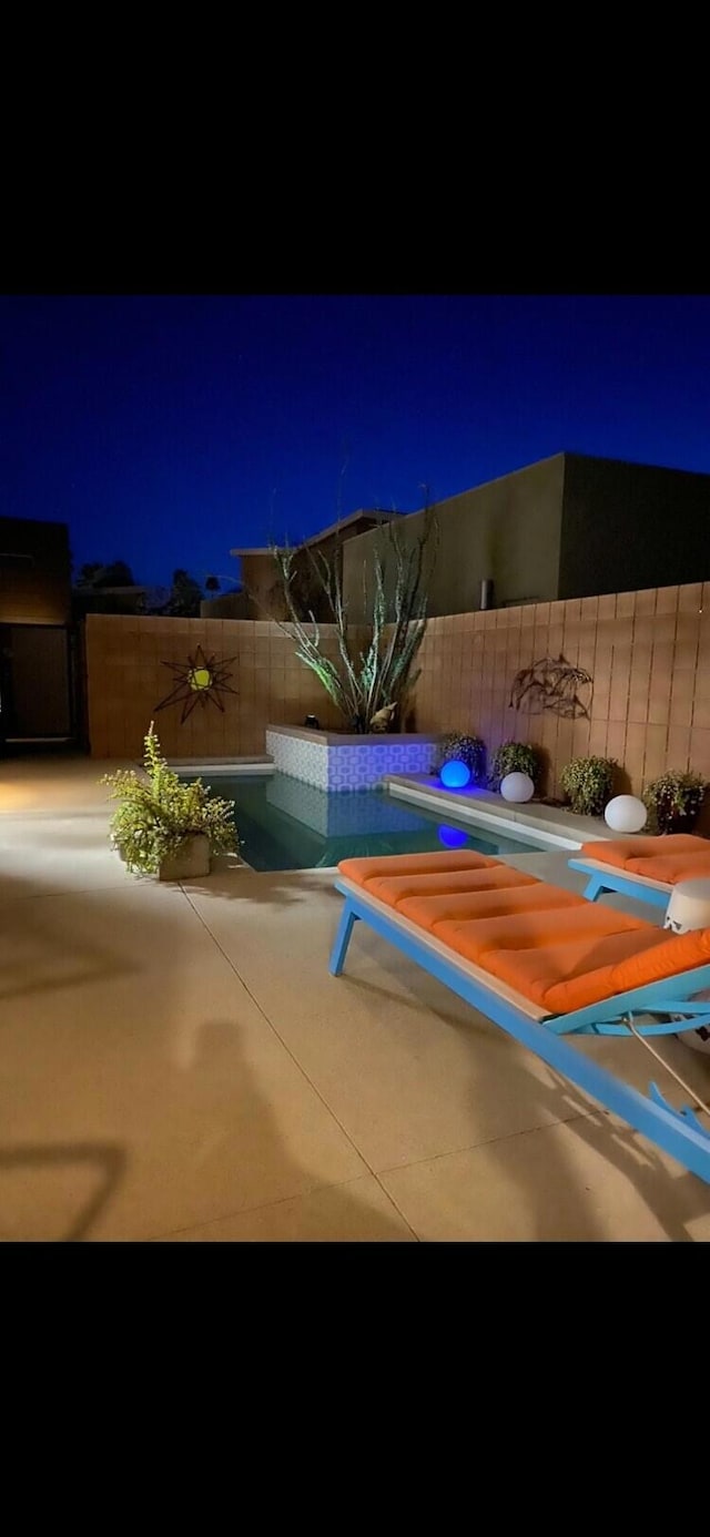 pool at night with a patio and a grill