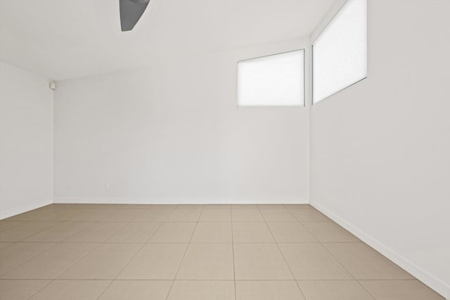 empty room with ceiling fan and light tile patterned flooring