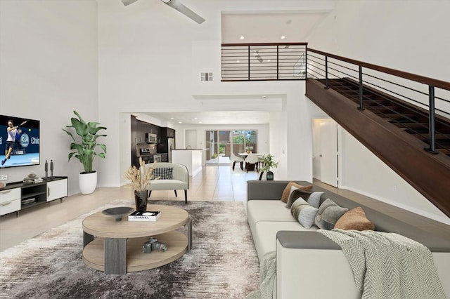 living room with ceiling fan, a towering ceiling, beamed ceiling, and light tile patterned floors