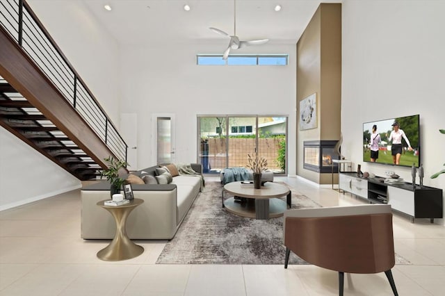 tiled living room featuring a high ceiling, a fireplace, and ceiling fan