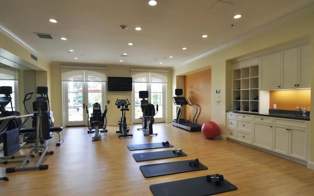 workout area featuring sink, ornamental molding, french doors, and light wood-type flooring