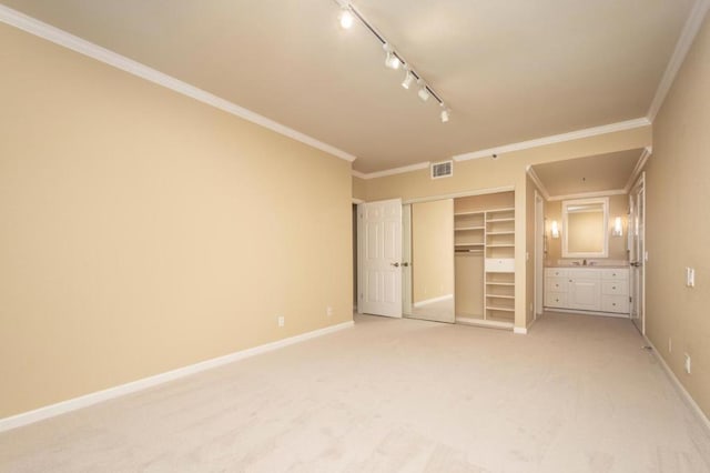 unfurnished bedroom featuring track lighting, a closet, ornamental molding, and carpet flooring