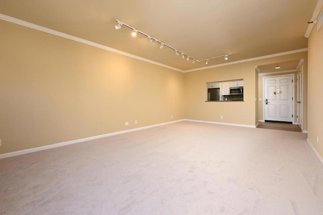 spare room with light carpet, crown molding, and track lighting