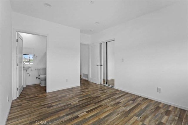 unfurnished bedroom featuring dark wood-type flooring, a closet, and connected bathroom