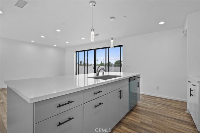 kitchen featuring decorative light fixtures, dishwasher, a kitchen island with sink, dark wood-type flooring, and sink