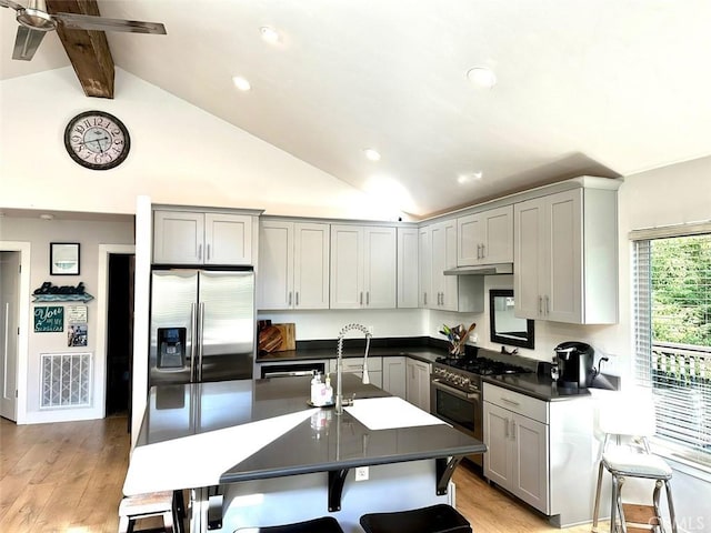 kitchen featuring sink, vaulted ceiling with beams, gray cabinetry, light wood-type flooring, and stainless steel appliances