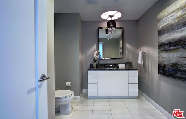 bathroom featuring toilet, tile patterned flooring, vanity, and a notable chandelier