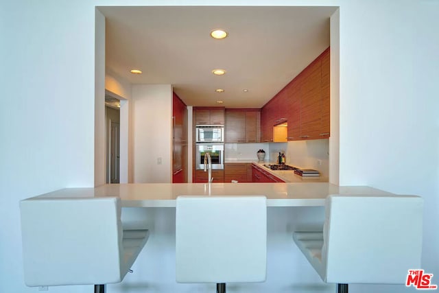 kitchen with appliances with stainless steel finishes, kitchen peninsula, and a breakfast bar area