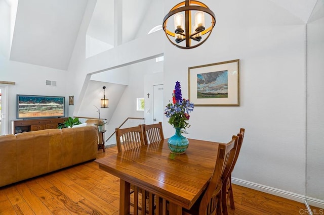 dining space with a notable chandelier, high vaulted ceiling, and hardwood / wood-style flooring