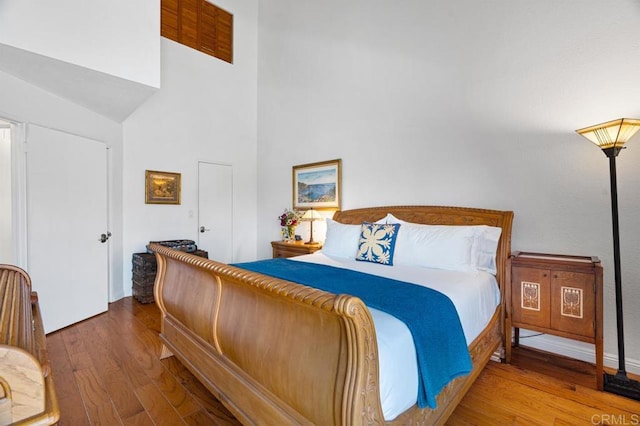 bedroom with high vaulted ceiling and hardwood / wood-style flooring