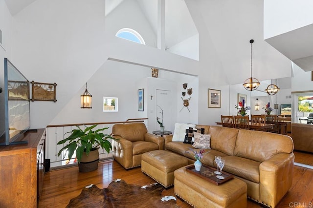 living room with high vaulted ceiling, hardwood / wood-style flooring, and an inviting chandelier