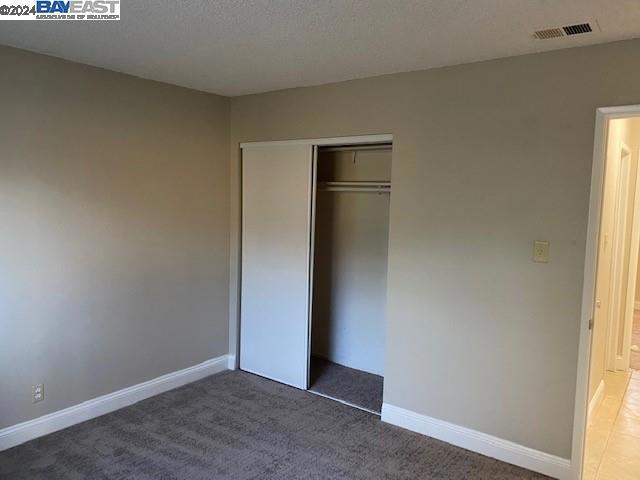 unfurnished bedroom featuring a closet, a textured ceiling, and carpet flooring