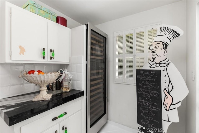 kitchen with dark countertops, wine cooler, white cabinetry, and tasteful backsplash