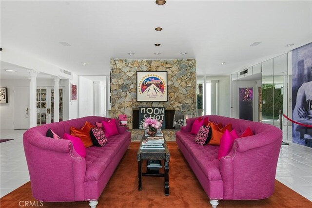 tiled living room with ornate columns and a fireplace