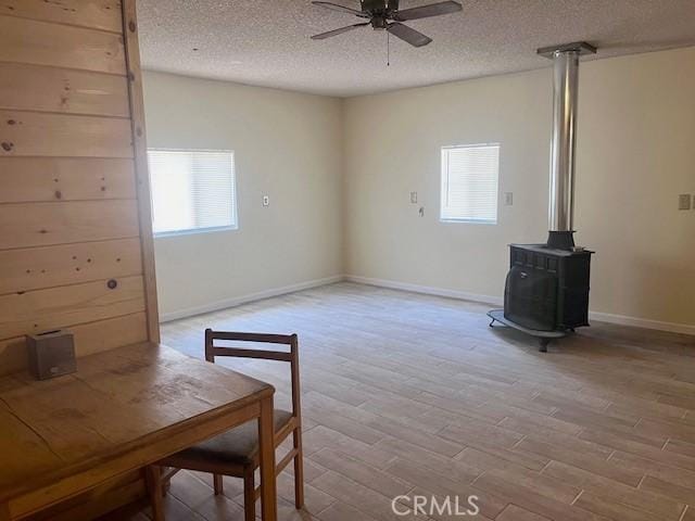 interior space featuring light hardwood / wood-style floors, a wood stove, a textured ceiling, and a wealth of natural light