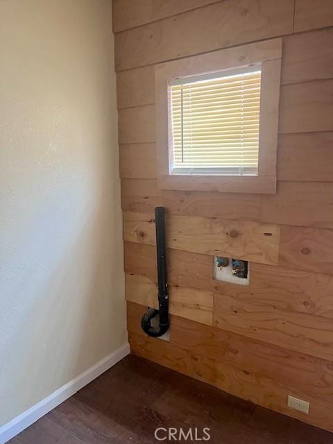 clothes washing area featuring washer hookup, wood walls, and dark wood-type flooring