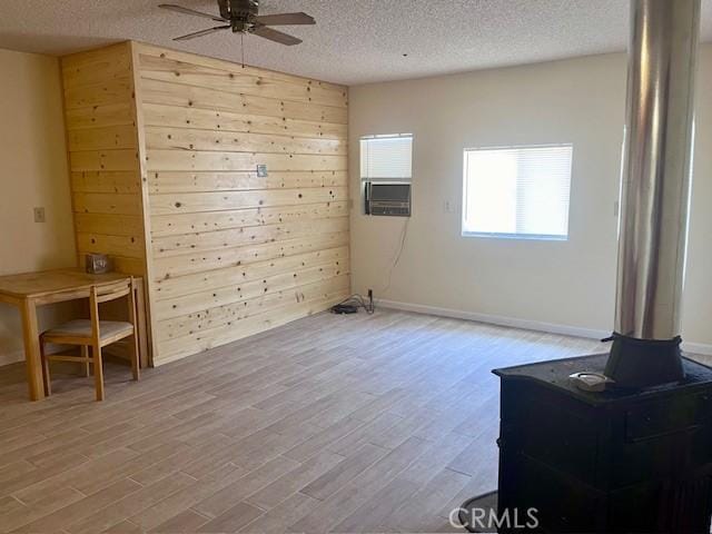 spare room with ceiling fan, cooling unit, a textured ceiling, and light wood-type flooring