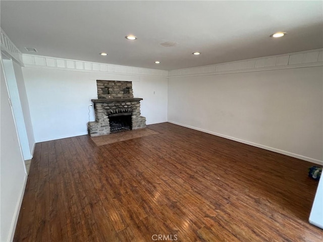 unfurnished living room with hardwood / wood-style flooring and a stone fireplace