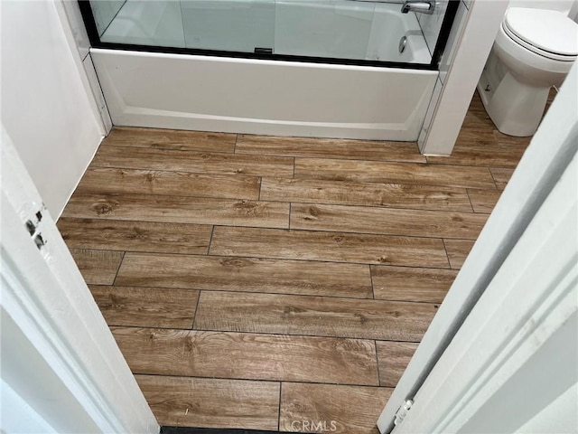 bathroom featuring toilet, combined bath / shower with glass door, and hardwood / wood-style flooring