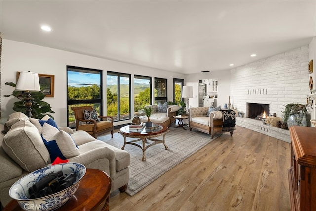 living room featuring light hardwood / wood-style floors, brick wall, and a brick fireplace