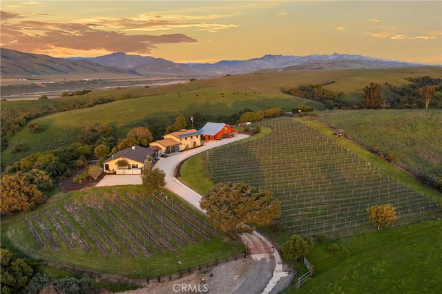 aerial view at dusk featuring a mountain view and a rural view