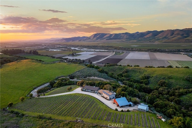 aerial view at dusk featuring a rural view and a mountain view