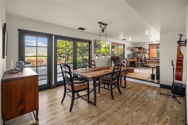 dining space featuring a wealth of natural light, light wood-type flooring, and french doors