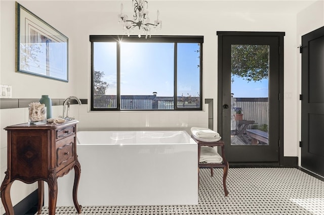 bathroom with a bathtub, tile flooring, a healthy amount of sunlight, and an inviting chandelier