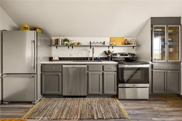 kitchen featuring appliances with stainless steel finishes, sink, lofted ceiling, and gray cabinetry