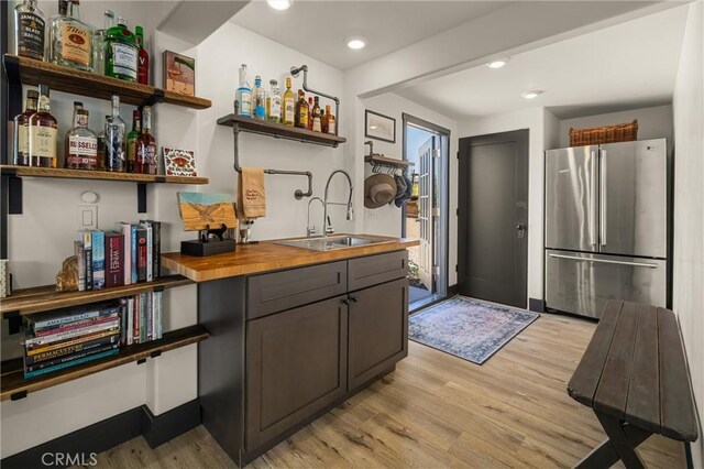 kitchen featuring sink, wood counters, stainless steel refrigerator, and light wood-type flooring