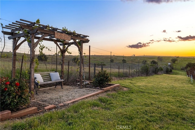 yard at dusk featuring a pergola and a rural view