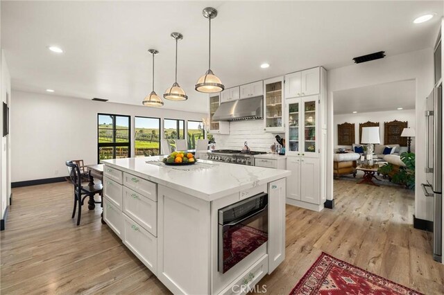 kitchen featuring white cabinetry, hanging light fixtures, backsplash, and light wood-type flooring