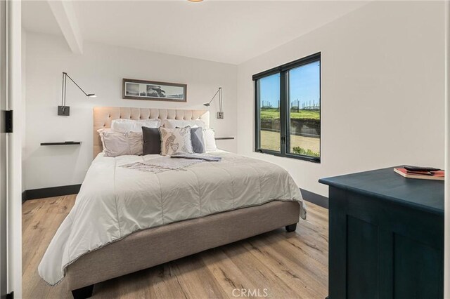 bedroom with beam ceiling and light hardwood / wood-style floors