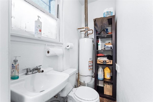 bathroom with sink, gas water heater, and toilet