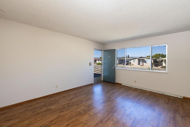 unfurnished room with a textured ceiling and dark hardwood / wood-style flooring