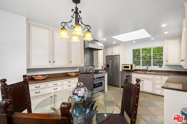 kitchen featuring white cabinets, appliances with stainless steel finishes, light tile floors, and a skylight