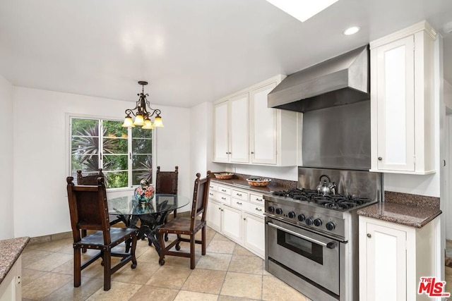 kitchen with high end stove, white cabinetry, wall chimney exhaust hood, and light tile flooring