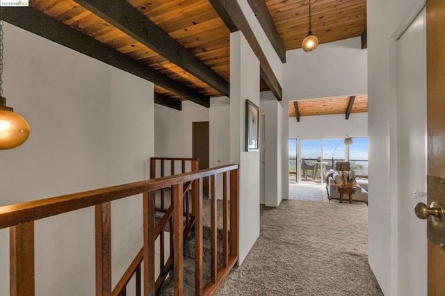 hallway with carpet flooring, a towering ceiling, wood ceiling, and beam ceiling