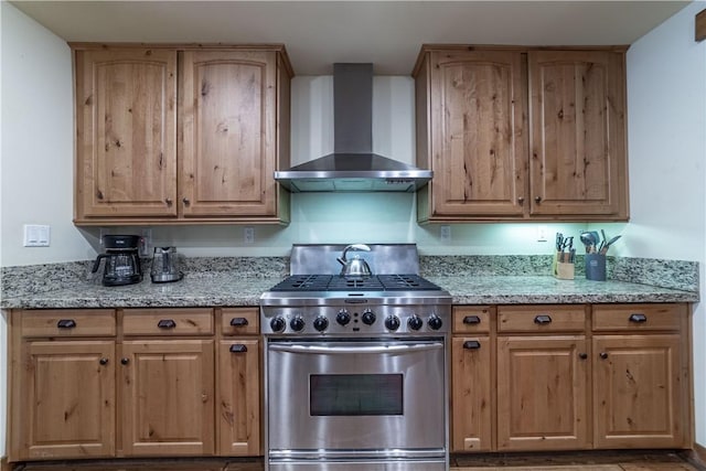 kitchen with light stone counters, high end stainless steel range, and wall chimney exhaust hood