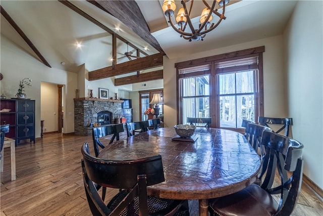 dining room featuring high vaulted ceiling, ceiling fan with notable chandelier, a fireplace, beam ceiling, and wood-type flooring