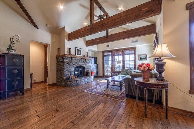 living room featuring beamed ceiling, wood-type flooring, high vaulted ceiling, and a wood stove