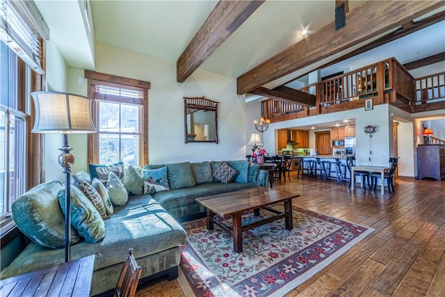 living room featuring beamed ceiling, a high ceiling, dark wood-type flooring, and a notable chandelier