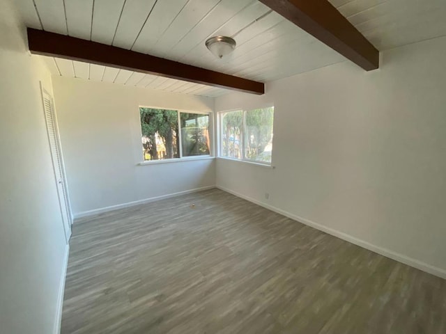 unfurnished room with beam ceiling and hardwood / wood-style floors