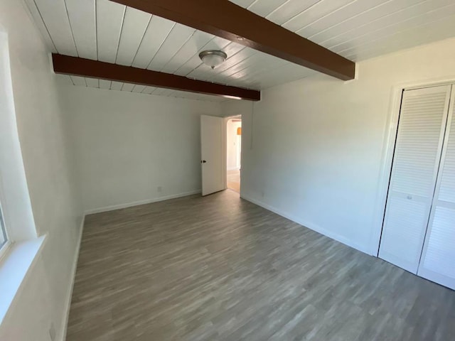 unfurnished bedroom with wooden ceiling, a closet, hardwood / wood-style floors, and beam ceiling