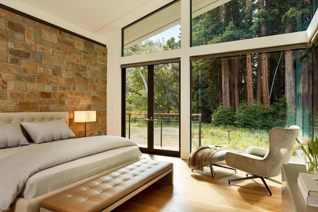 bedroom featuring french doors, wood-type flooring, access to exterior, and multiple windows