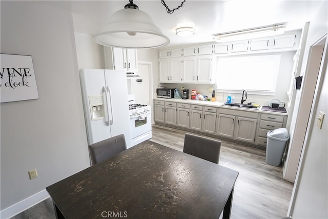 kitchen with pendant lighting, light wood-type flooring, sink, and white appliances